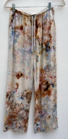 a pair of pants hanging on a hanger with paint splatters all over them