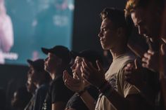 a group of people standing next to each other in front of a screen with their hands together