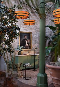 a painting on the wall next to a table with chairs and potted plants in front of it