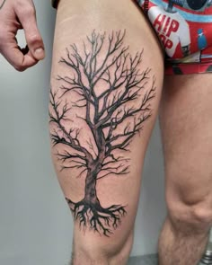 a man's leg with a tree tattoo on the side of his thigh,