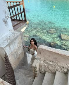 a woman is standing on some stairs by the water