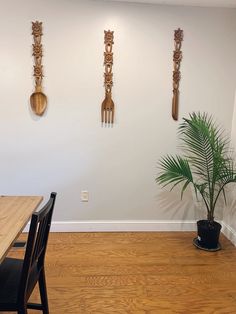 three wooden utensils hang on the wall above a dining room table and chairs