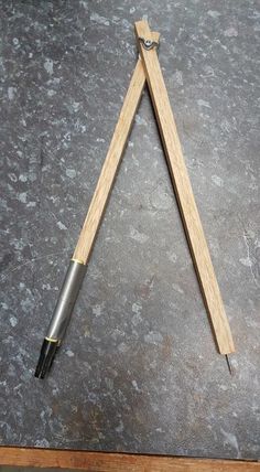 a pair of wooden clothes pins sitting on top of a gray floor next to a piece of wood