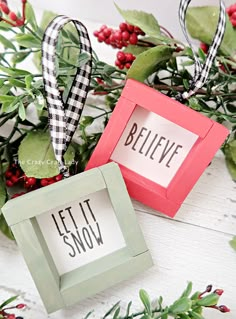 two small frames with words on them sitting in front of some holly branches and berries