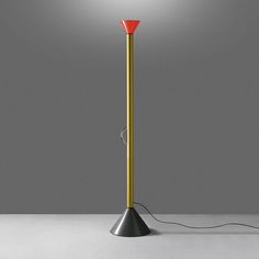 a floor lamp with a red light on it and a cord attached to the base