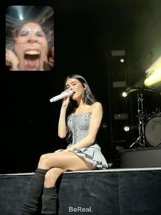 a woman sitting on top of a stage with a microphone in front of her face