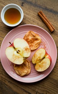 apples and cinnamon on a pink plate next to a cup of tea