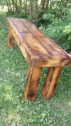 a wooden bench sitting on top of a lush green field next to trees and bushes