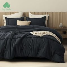 a bed with black comforter and pillows in a room