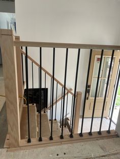 a stair case with black railing and wooden handrails in an unfinished room next to a door