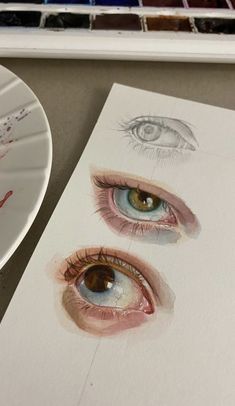 a paper plate with some watercolors on it next to an eyeball and paintbrush