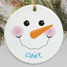 a personalized snowman ornament hanging from a christmas tree with pine cones