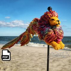 a stuffed animal is on top of a pole at the beach, with an ocean in the background