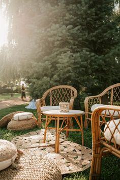 wicker chairs and tables are set up on the grass in front of some trees