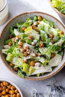 two bowls filled with lettuce and chickpeas next to a bottle of milk