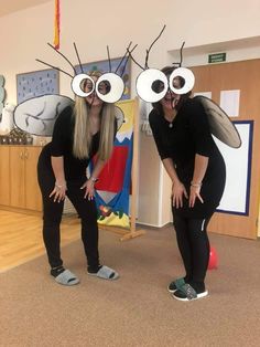 two women dressed up in costumes with large eyes and antennae on their heads, standing next to each other