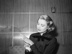 a black and white photo of a woman sitting on a couch holding her hands together