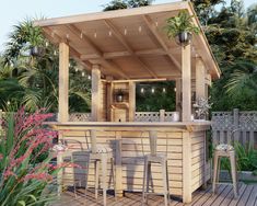 an outdoor bar with stools and lights on the roof is surrounded by greenery