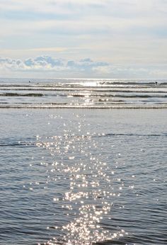 the sun shines on the water as it reflects off the sand at the beach