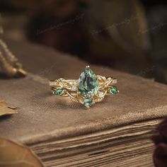 a green ring sitting on top of an old book with leaves around it and stones in the middle