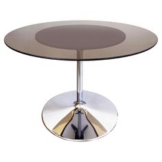 a round glass table with chrome base and circular metal plate on the top, against a white background