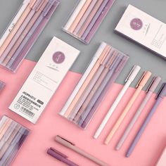 several different types of pencils and pens on a pink surface with the same color