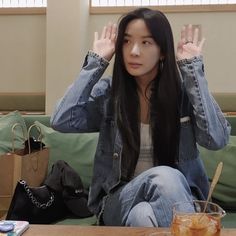 a young woman sitting on top of a couch holding her hands up to her head