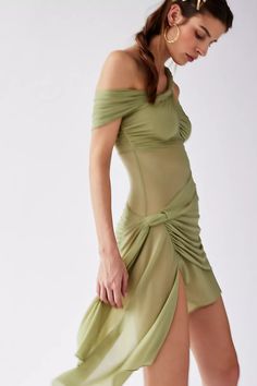 a woman in a green dress is posing for the camera with her hand on her hip