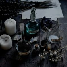 candles, bottles and other items on a wooden table with writing paper in the background