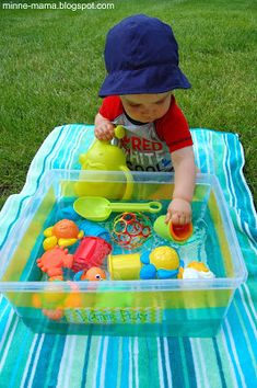 a baby playing with toys on a blanket in the grass