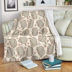 a cat print blanket sitting on top of a wooden floor next to a white couch