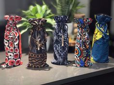 four vases sitting on top of a counter next to a potted plant