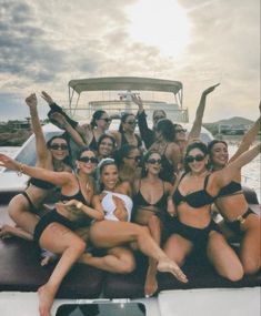 a group of women in swimsuits on a boat posing for a photo together