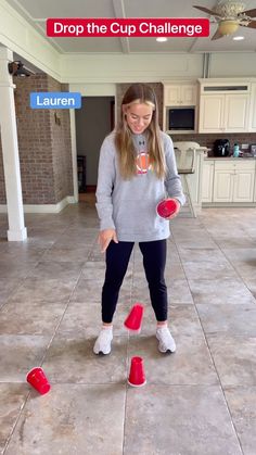 a girl is playing with red cups in the middle of a floor that has been made to look like they are falling