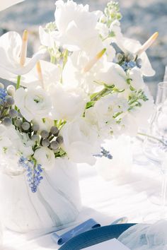 a vase filled with white flowers sitting on top of a blue and white table cloth