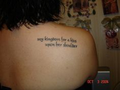 a woman with a tattoo on her back saying, my kingdom for a kiss upon her shoulder