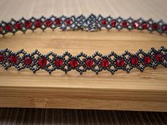 a red and black beaded bracelet on a wooden table