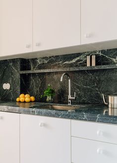 a kitchen with marble counter tops and white cupboards next to a stainless steel sink