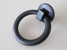 a metal ring on a white surface with a black handle that is attached to it