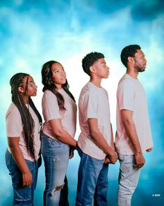 a group of people standing next to each other in front of a blue sky with clouds