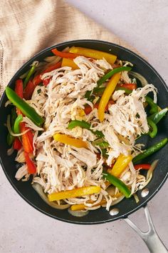 a skillet filled with chicken, peppers and green beans on top of a table