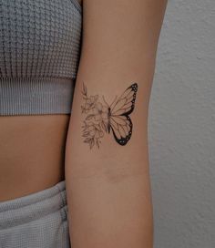 a woman's arm with a butterfly and flower tattoo on the left side of her arm