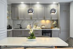 a kitchen with grey cabinets and white countertops is seen in this image from the dining room