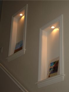 two white framed pictures are hanging on the wall next to some recessed light fixtures