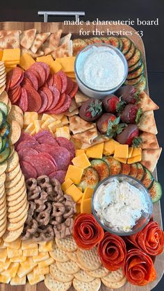 a platter filled with crackers, cheeses and other food on top of a wooden table