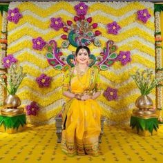 a woman sitting on a bench in front of a yellow wall with flowers and decorations