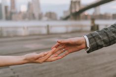 two people reaching out their hands to each other in front of a cityscape