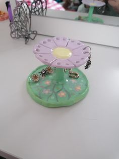 a flower shaped object sitting on top of a white counter next to a mirror with people in the background