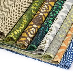 several fabrics are stacked on top of each other in different colors and patterns, including blue, green, brown, yellow