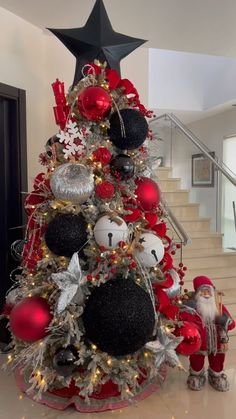 a christmas tree decorated with black and white ornaments, red balls and silver tinsel